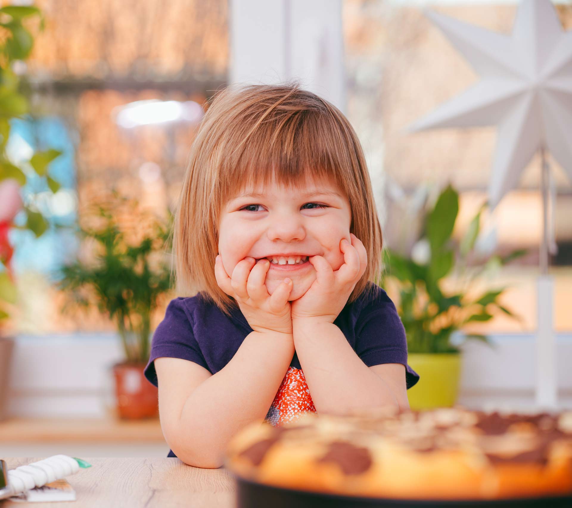 Child smiling sitting at a table with food